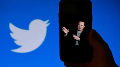 In this photo illustration, a phone screen displays a photo of Elon Musk with the Twitter logo shown in the background, on October 4, 2022, in Washington, DC. Elon Musk has offered to push through with his buyout of Twitter at the original agreed price, reports said Tuesday, prompting a surge in the share price of the social network that triggered a suspension of trading. OLIVIER DOULIERY / AFP